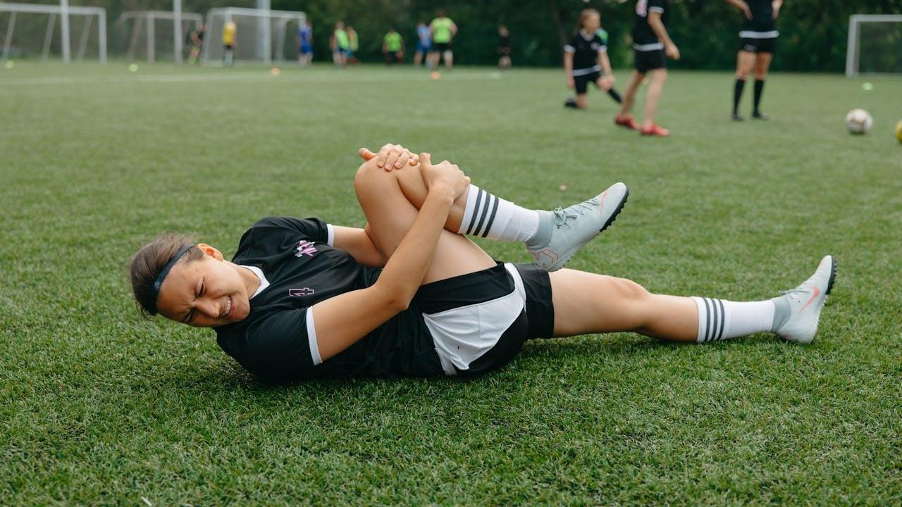 Futbolista en el pasto con dolor de rodilla