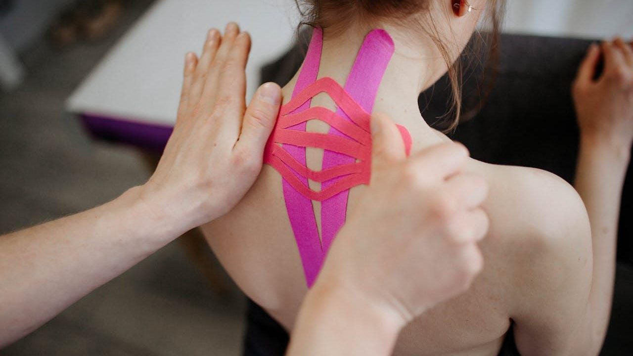 Vendaje neuromuscular rosa en el cuello y la espalda alta
