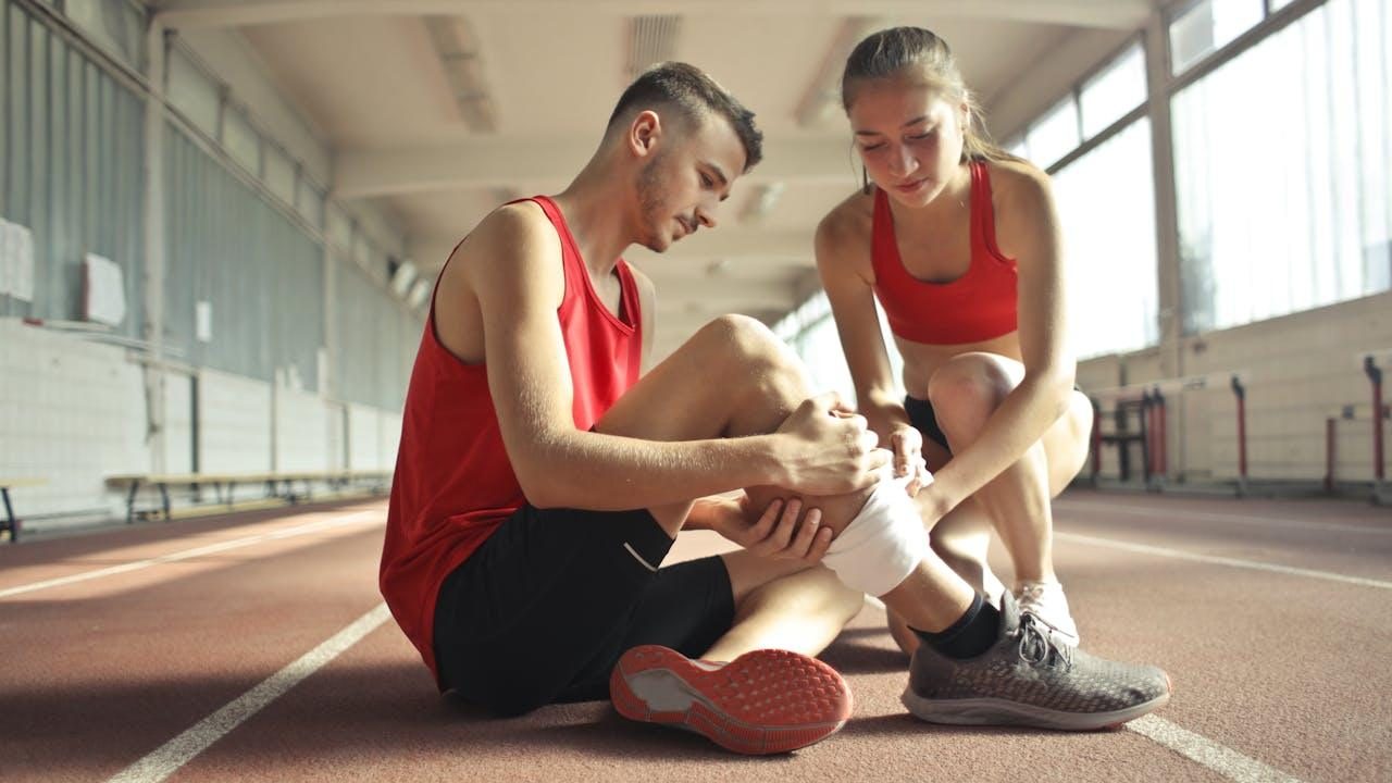 Deportista con lesión en el tobillo en una pista de atletismo