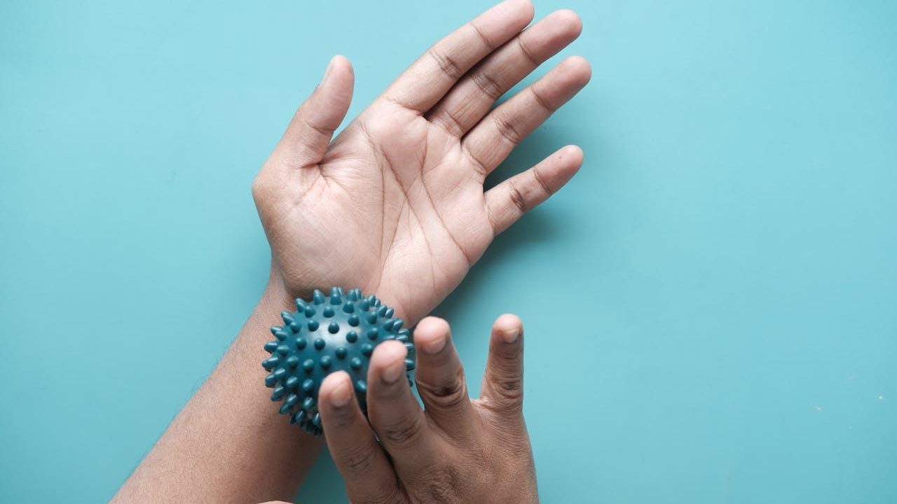 Mano con pelota de masaje con picos para terapia manual
