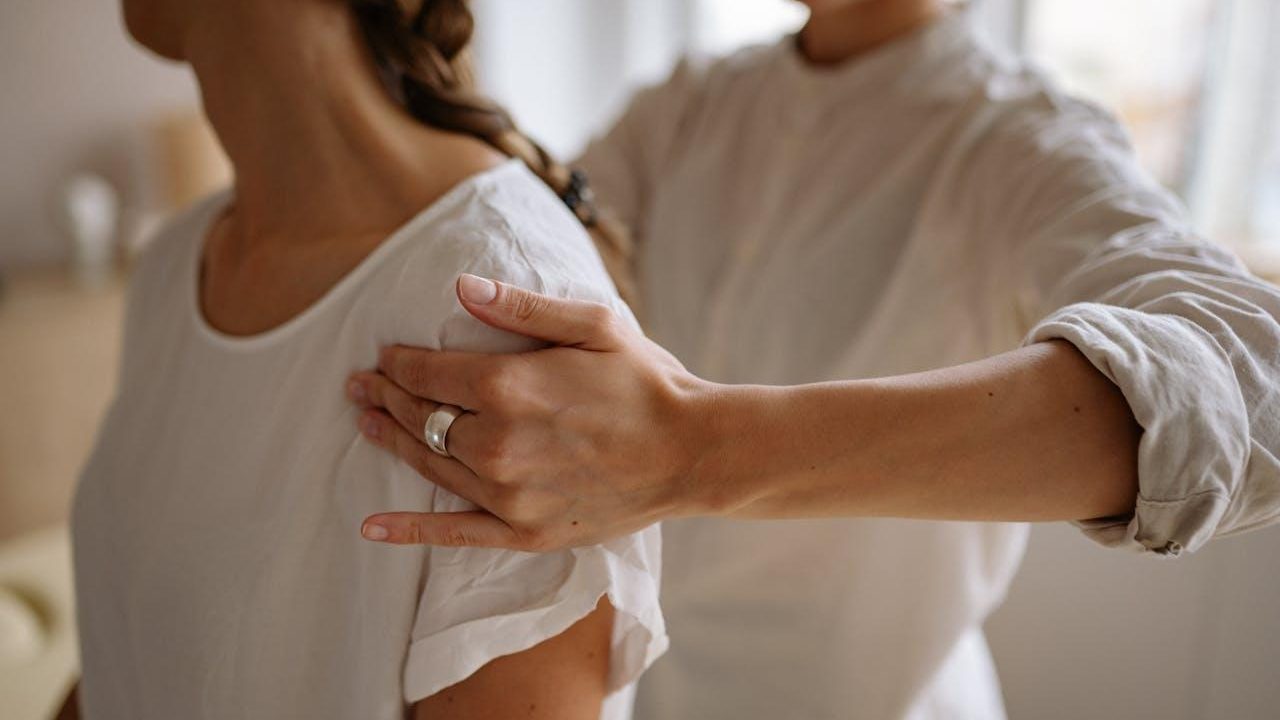 Fisioterapeuta revisa el hombro y el brazo de una paciente