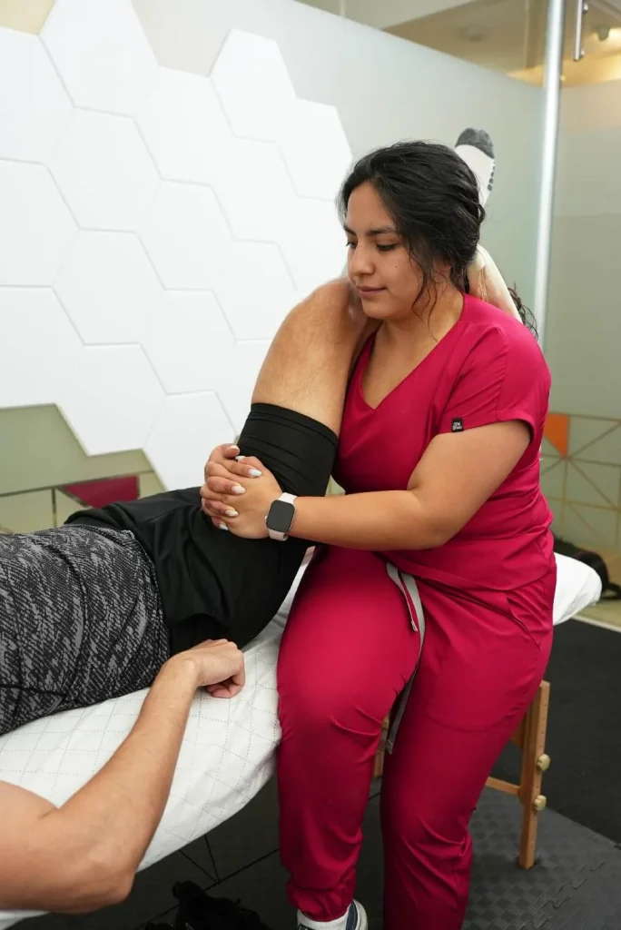Fisioterapeuta moviliza el hombro de un paciente acostado
