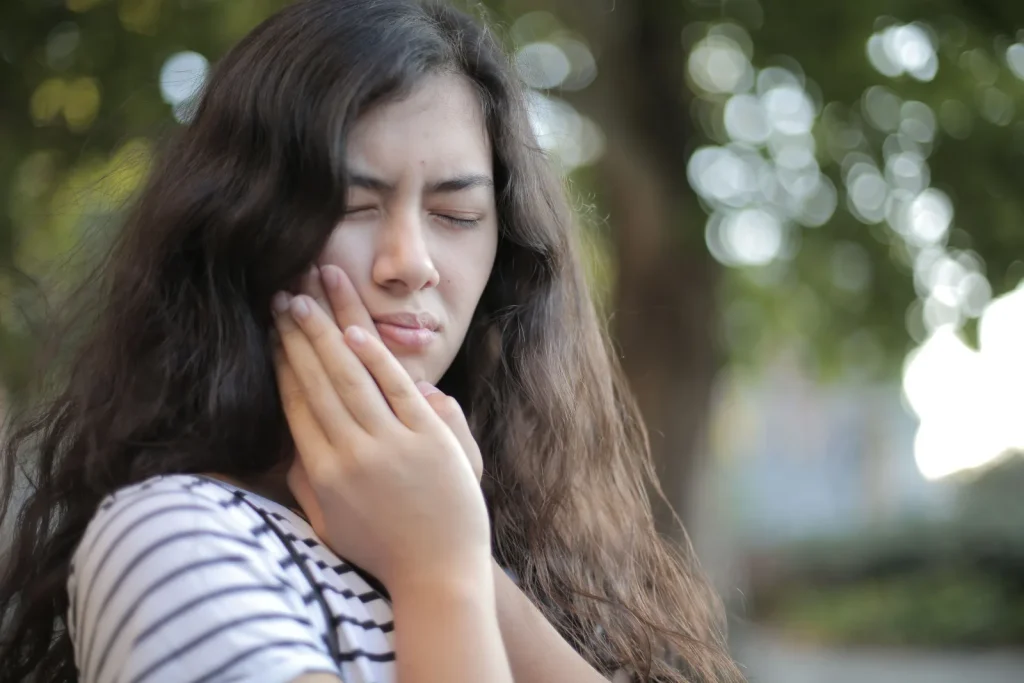 Mujer con dolor en la mandíbula se sujeta la cara